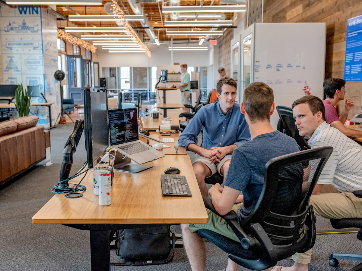 Professionals having a conversation in a shared workspace; an illustrative photograph from the RemoRoute image library.